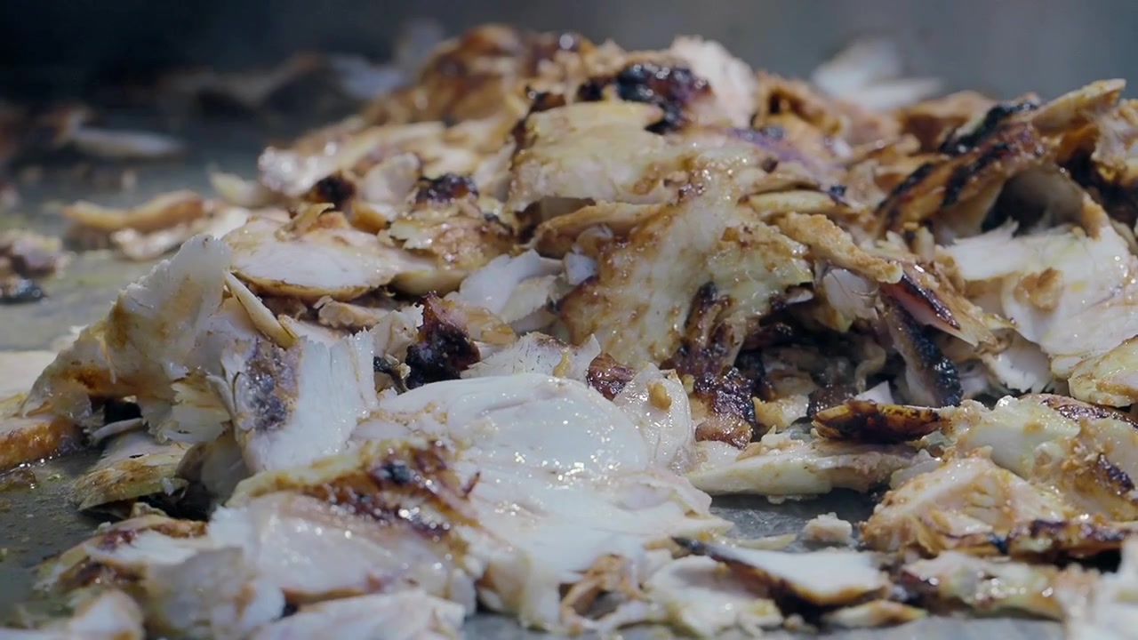 Chef che soffrigge shawarma di pollo a fette su una piastra calda