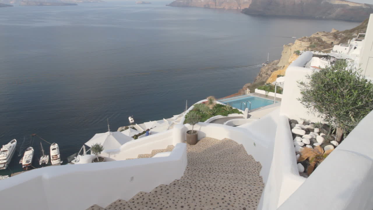 mirando hacia abajo a los acantilados y villas de vacaciones que envuelven el mar egeo en oia, santorini