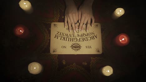 ouija board with hands and candles