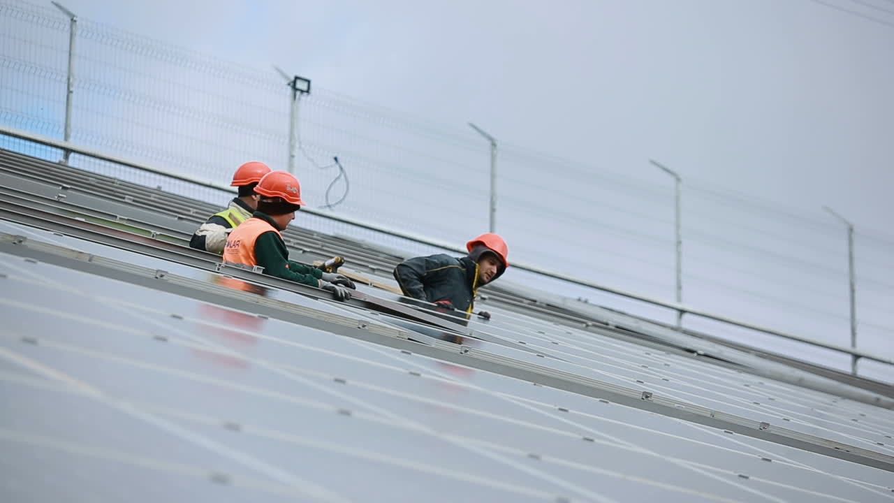 Worker install solar panels. VINNITSA, UKRAINE - NOVEMBER 2017: Workers in uniform and hardhat install solar panels on solar farm