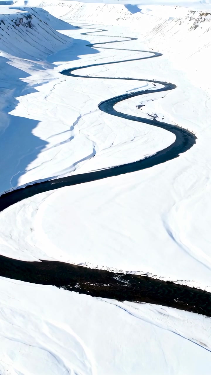 Vertical video: Drone moving forward over snow plain, revealing S-shaped river for travel designers