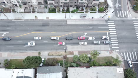 el tráfico se detiene en una intersección de luz roja en un bulevar en los ángeles cerca de condominios