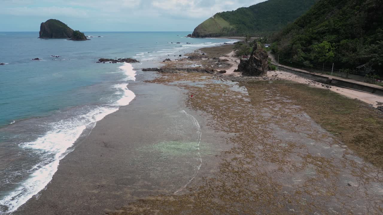 A smooth drone shot glides over the shoreline, showcasing the calm ocean gently kissing the sand.