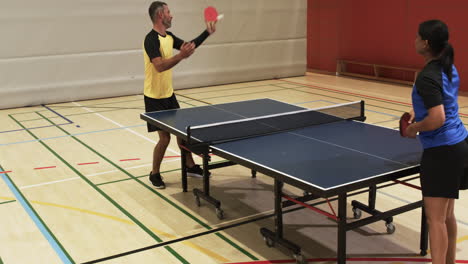 playing table tennis, man in yellow shirt hitting ball in indoor court