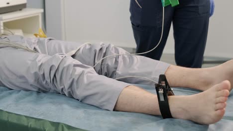 examen cardíaco en un hospital con un cardiógrafo profesional. el paciente se acuesta en una cama con sensores conectados.