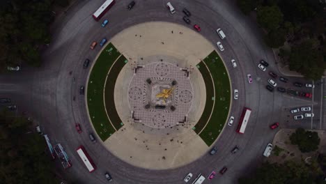 cinematic drone shot of the angel of independence while vehicles circulate in the roundabout during a cloudy day