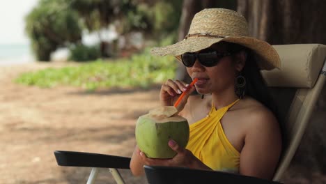 image of a woman relaxing near the beach while drinking fresh coconut juice