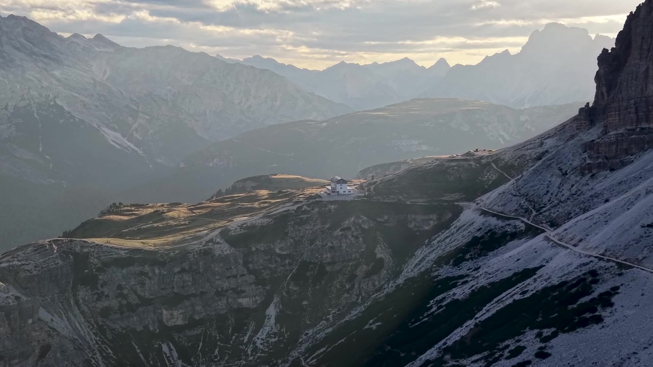 Vista drone del Rifugio Auronzo circondato da maestose vette alpine al tramonto alle Tre Cime di Lavaredo nelle Dolomiti, Italia