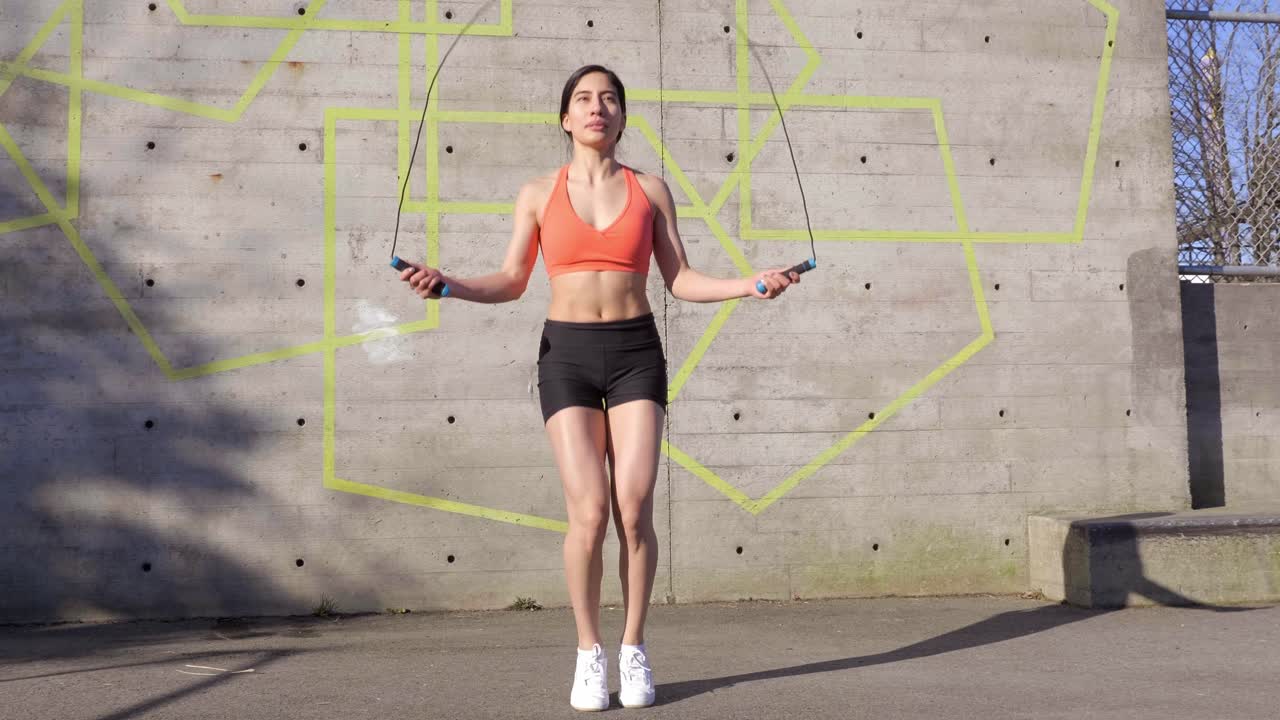 mujer joven en forma saltando al aire libre bajo el sol gran angular