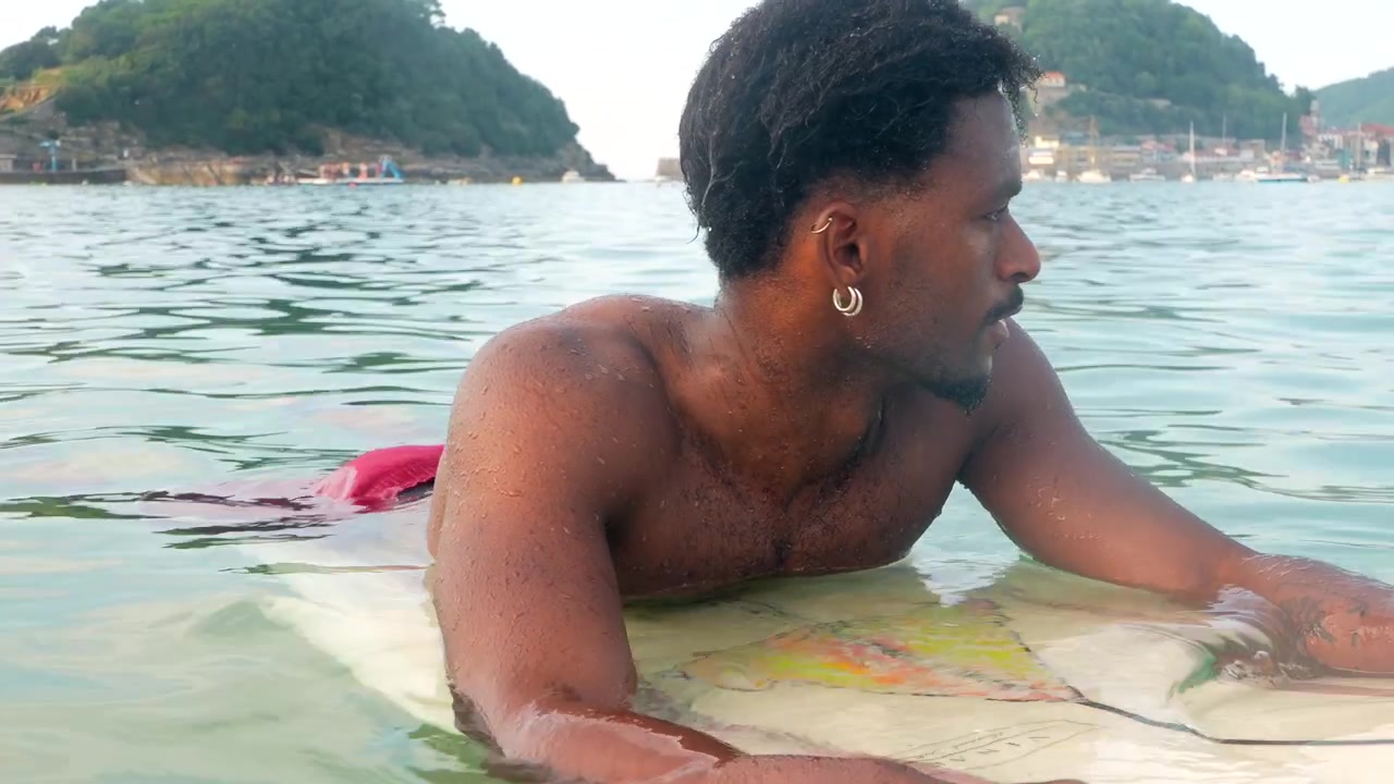 Jeune homme se reposant sur sa planche de surf dans les eaux calmes de l'océan