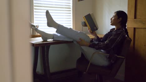 mujer puertorriqueña cómoda leyendo un libro de historias inspiradoras con los pies levantados descansando en el escritorio