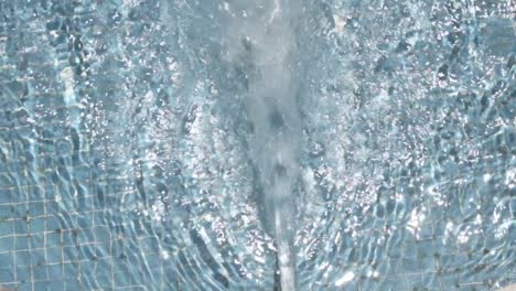 Powerful water jet filling a swimming pool with some floats and rubbish in water, needing maintenance and filtration for hygiene and enjoyment