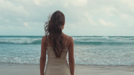 happy young woman enjoying sunrise at beach. girl looking to waves at coastline.