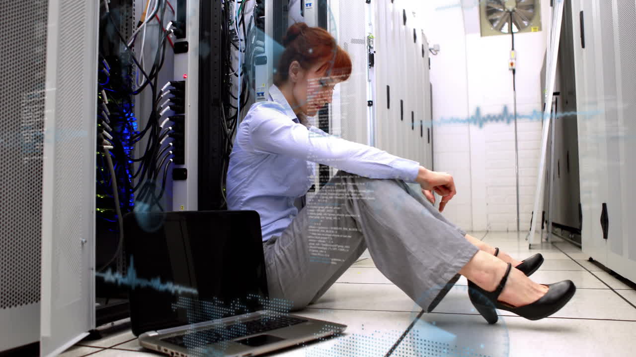 Sitting on floor in server room, woman using laptop and watching animation