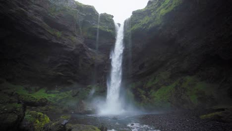 A-waterfall-in-Iceland,-surrounded-by-tall-cliffs---Slow-motion