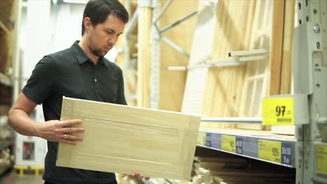 man shopping for wood panels at a hardware store