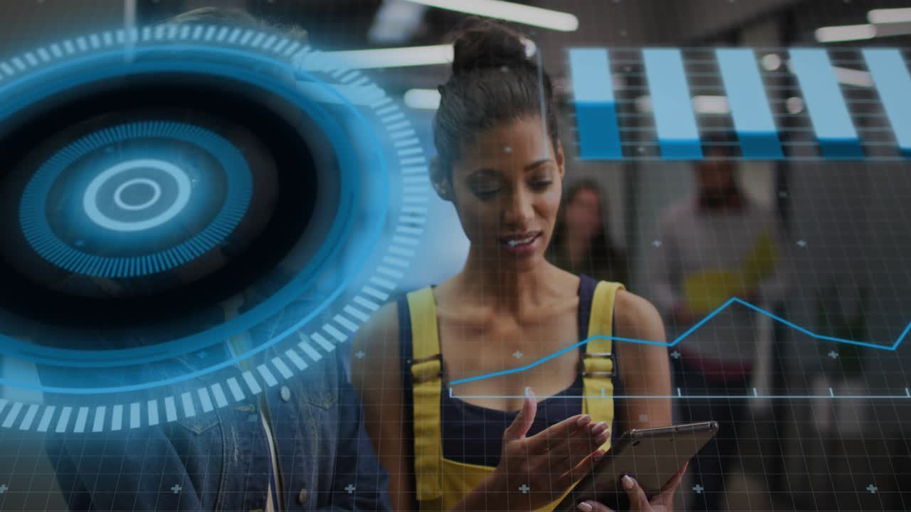 Woman in yellow overalls holding tablet, peer tapping screen initiating HUD chart for tech review