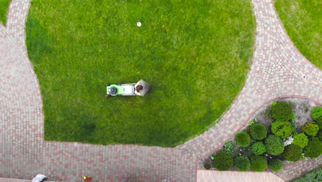 vista aérea de un trabajador cortando césped verde con una máquina herramienta de cortadora motorizada o eléctrica.