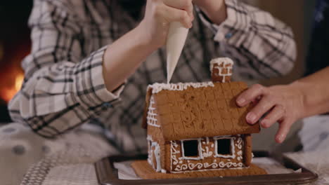 familia decorando una casa de pan de jengibre junto a la chimenea