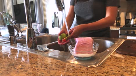 motion-shot,-zooming-in-on-female-hands,-washing-dishes,-at-a-home-kitchen,-in-Los-Angeles