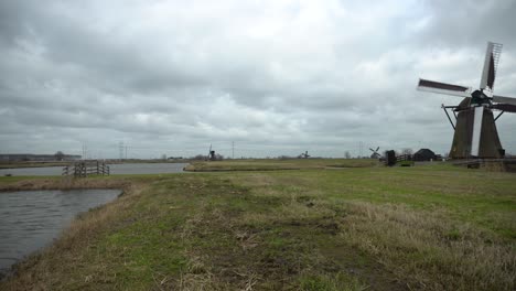 Holländische-Windmühlen-Drehen-Sich-In-Feuchtgebieten,-Kameraschwenk-Enthüllt