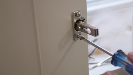 slow motion close up of a woman screwing a screw into a closet latch of a white wardrobe