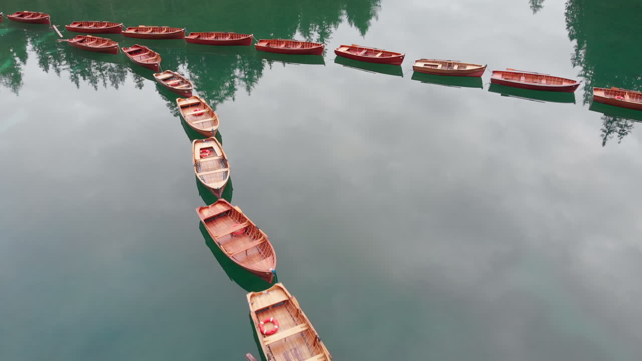 toma aérea de un dron sobre barcos alineados en el lago braies en los dolomitas, italia