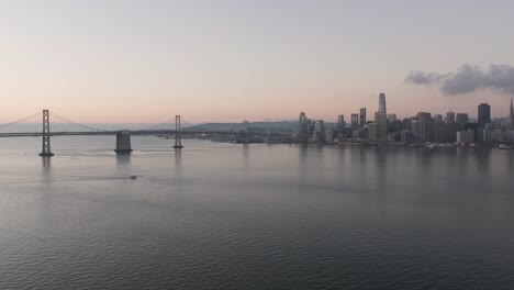 Luftrückzug-Im-Morgengrauen,-Weiter-Blick-Auf-Die-Skyline-Von-San-Francisco-Und-Die-Oakland-Bay-Bridge