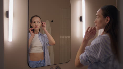 girl reflection combing hair in soft bathroom light. attractive woman styling