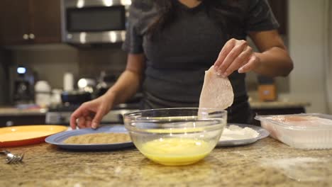 close up shot of a female preparing chicken in a breading and egg bater, for dinner, los angeles, california