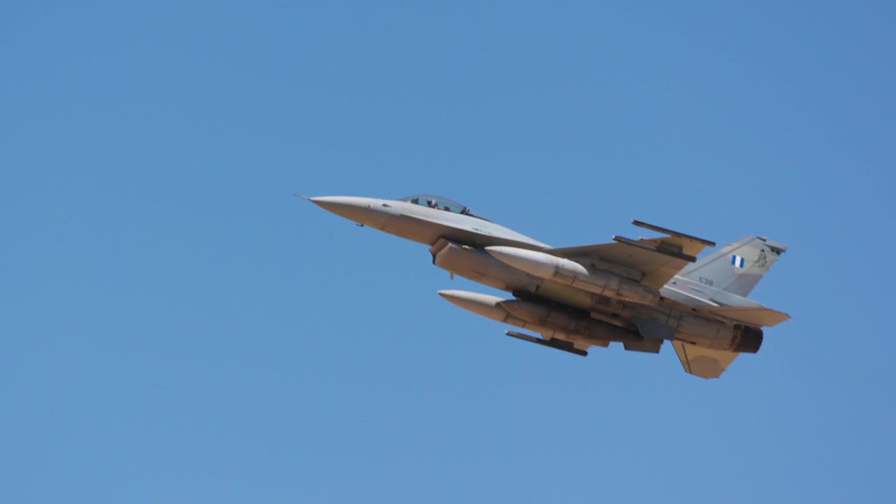 Ein militärischer Kampfjet steigt in Zeitlupe durch einen klaren blauen Himmel auf und schwebt während eines Tagesflugs nach oben.