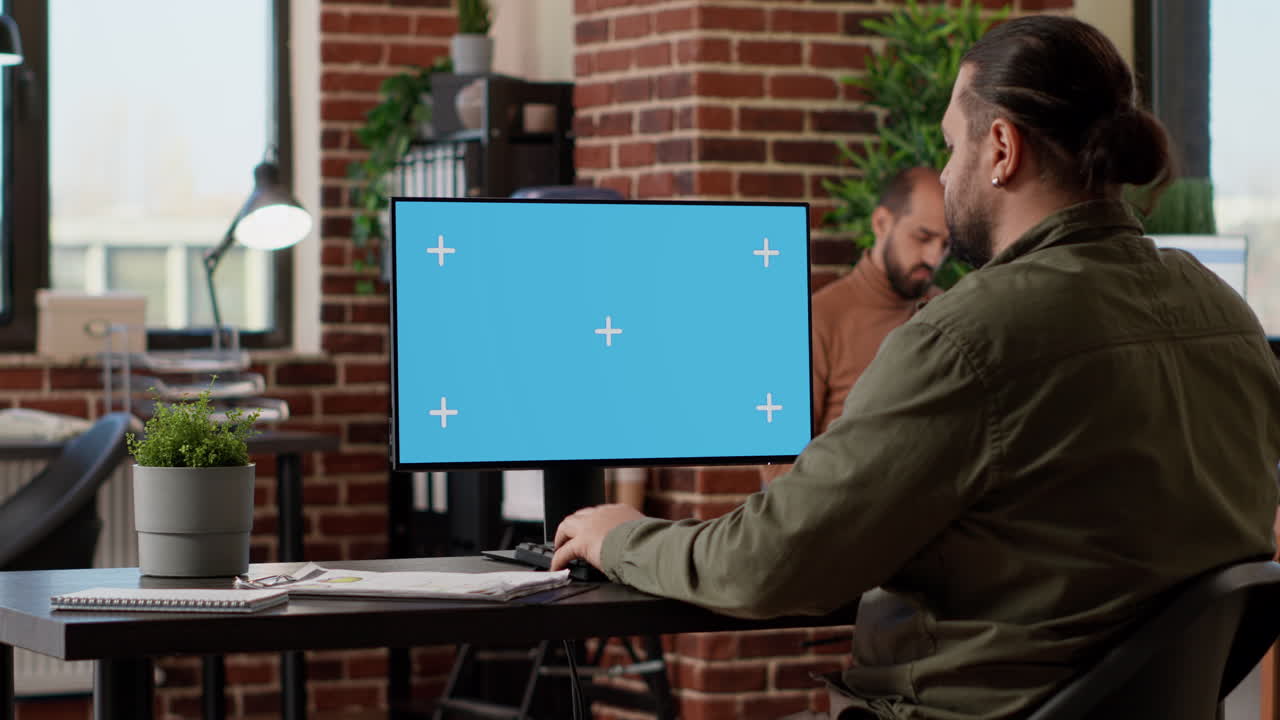 Office employee typing on computer with greenscreen