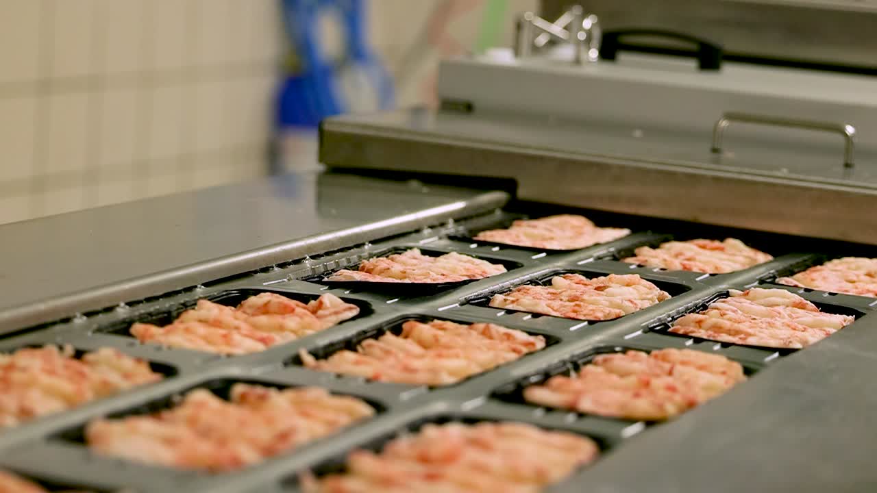 el trabajador de guantes colocó bandejas negras de camarones o mariscos en el soporte de la cinta transportadora