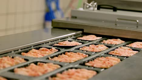 Gloves-worker-placed-black-trays-of-shrimp-or-shellfish-onto-holder-in-conveyor-belt