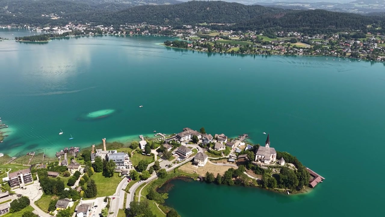 Luftaufnahme des malerischen Dorfes Maria Wörth am Wörthersee in Österreich an einem sonnigen Sommertag, Drohnenaufnahme