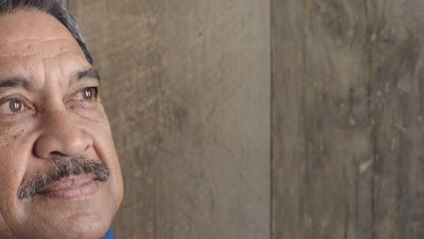 half-face-portrait-of-middle-aged-hispanic-man-looking-pensive-contemplative-at-camera-on-wooden-background-close-up