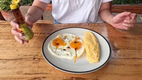 persona aderezando huevos y tortilla en un plato