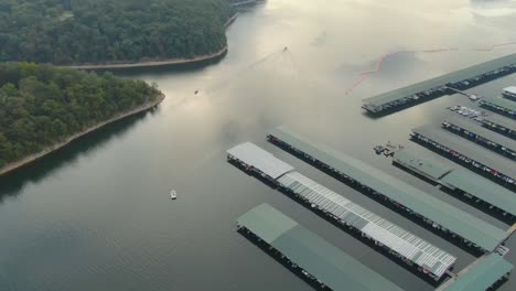 Hovering-aerial-view-of-boats-departing-large-lake-marina-early-in-the-morning