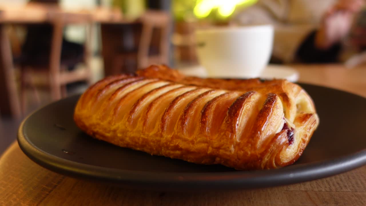 Close-up of a golden brown pastry on a dark plate in a cafe