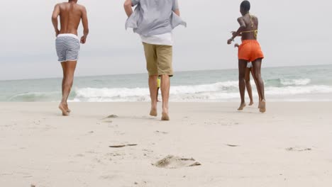 rear view of mixed-race friends running towards sea at beach 4k