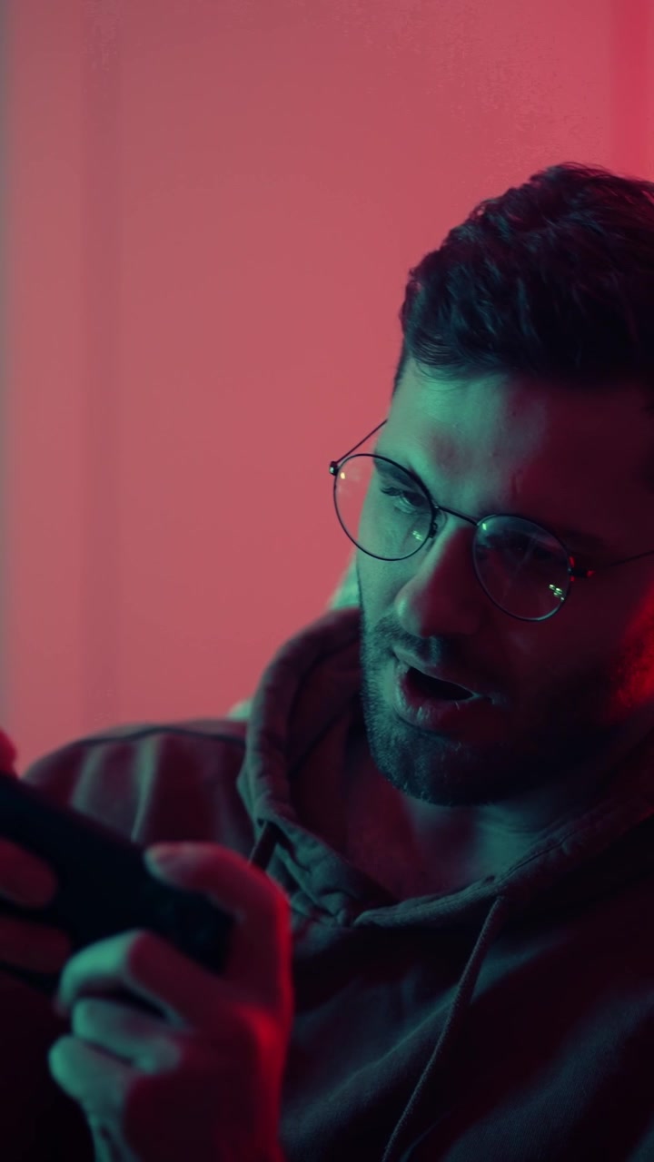 Giovane uomo che gioca ai videogiochi con un controller in una stanza illuminata al neon