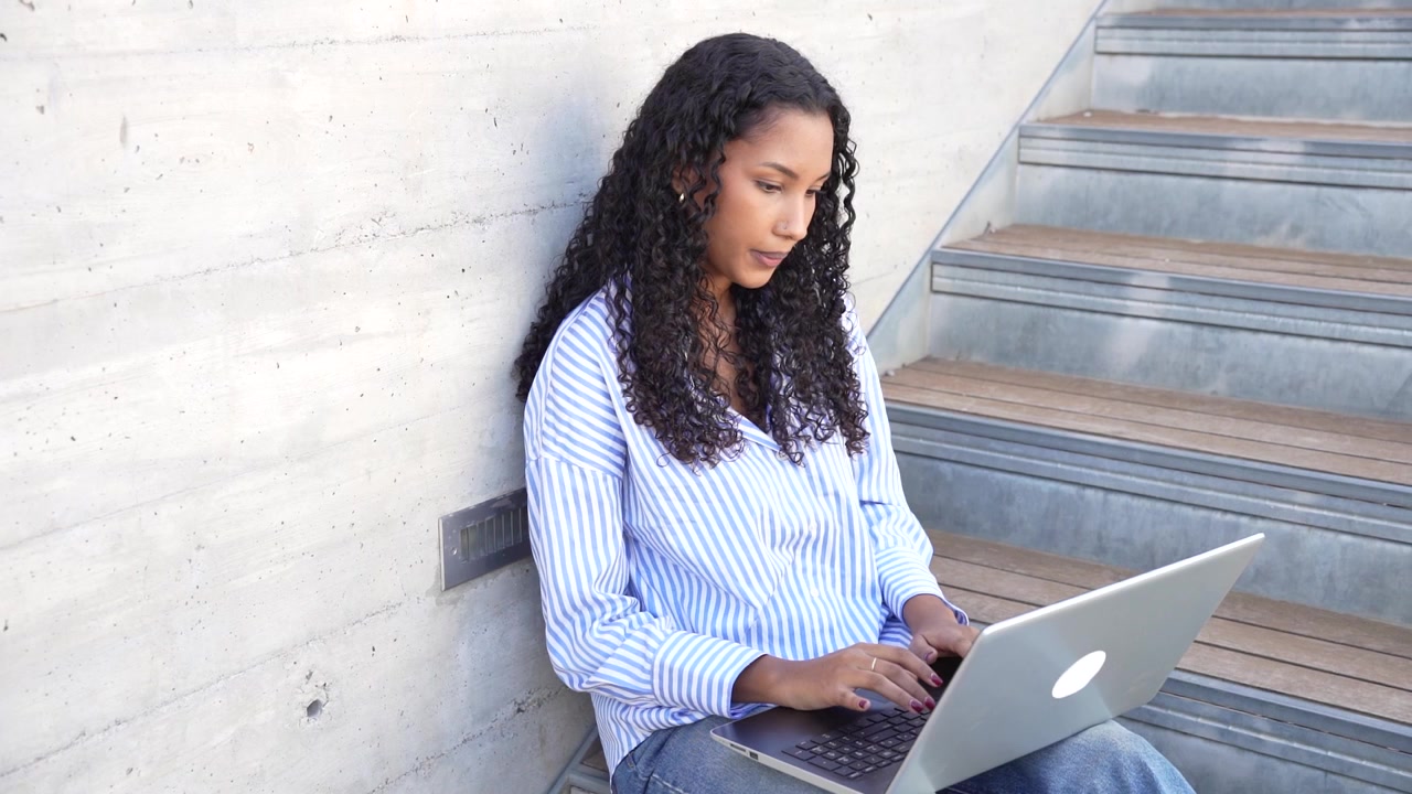 A young woman engaged in working on her laptop while outdoors embracing natures beauty