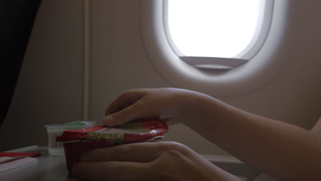 close up clip of woman eating airplane dinner rise with vegetables by plastic fork against window