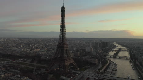 Slide-and-pan-footage-of-Eiffel-Tower-and-large-city-at-dusk-in-background.-Tall-historic-steel-structure-with-lookout-platforms.-Paris,-France