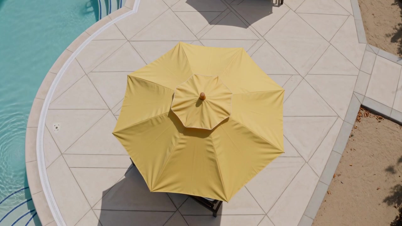 Ombrellone da patio giallo che si apre sopra le sedie a sdraio sul bordo piscina mentre il meccanismo si muove, fornendo ombra.