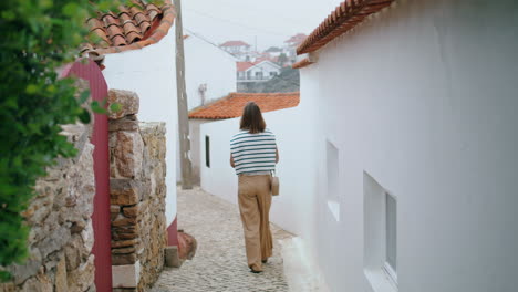 una chica romántica caminando por una vieja calle estrecha vertical. un turista despreocupado explora la ciudad.