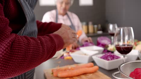 una pareja biracial mayor pelando y cortando verduras en la cocina, sin alterar, en cámara lenta