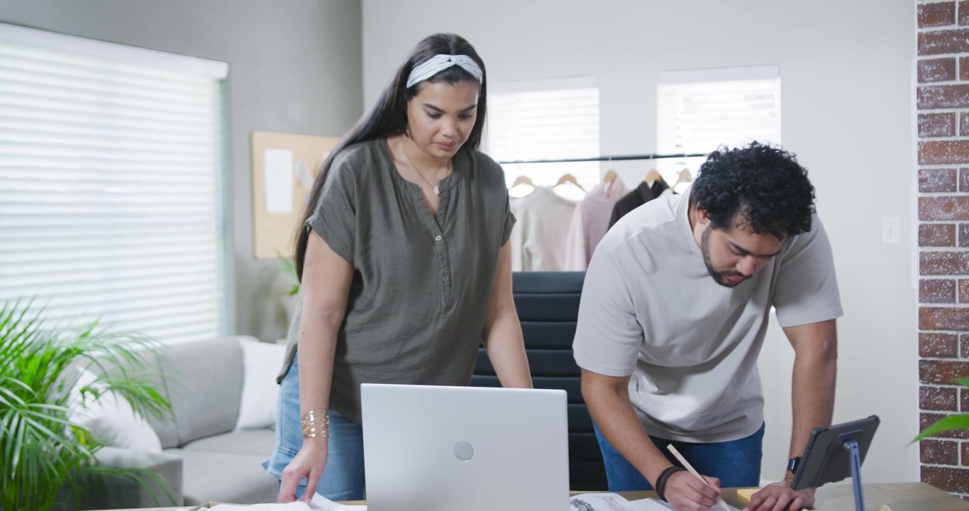 Partner afroamericani, un uomo che prende appunti, una donna che controlla il laptop e i campioncini di colore, mentre ordinano in studio.