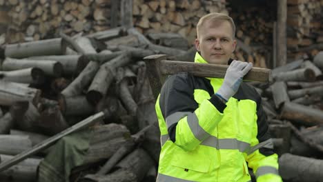 lumberjack in reflective jacket. man woodcutter with big axe. sawn logs, firewood background