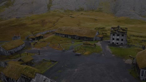 Aerial-pullback-from-viking-village-film-set-with-foggy-Vestrahorn-mountain-Background,-Iceland